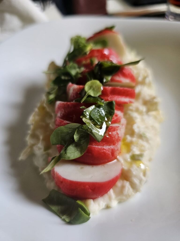 Ensalada de patata, huevo y manzana con surimi presentada en un plato blanco